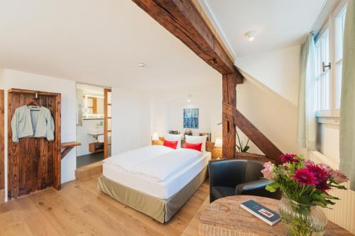 a bedroom with a bed and a chair and a table at Tailormade Hotel RÜDEN Schaffhausen in Schaffhausen