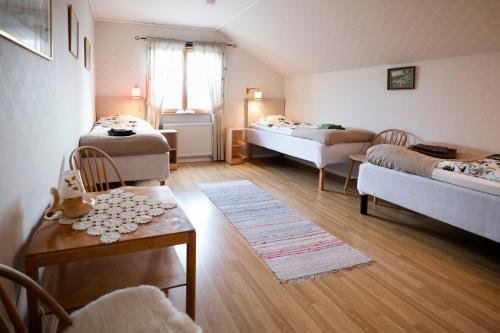 een kamer met 2 bedden en een tafel en stoelen bij Mellangården in Västerbykil