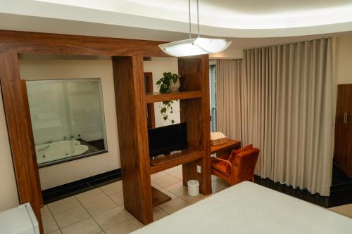 a living room with a television and a bathroom at Hotel Canaan in Sete Lagoas
