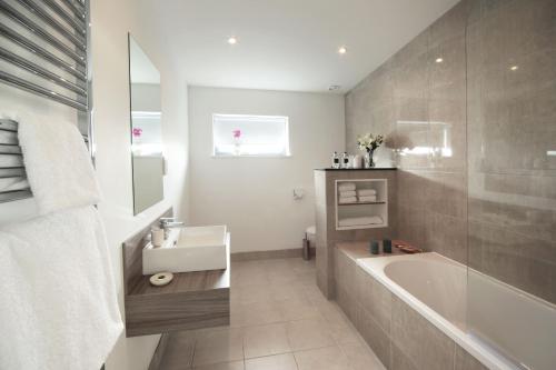 a bathroom with a bath tub and a sink at Jog Lodge 13 By Together Travel - 3 Bed in John O Groats
