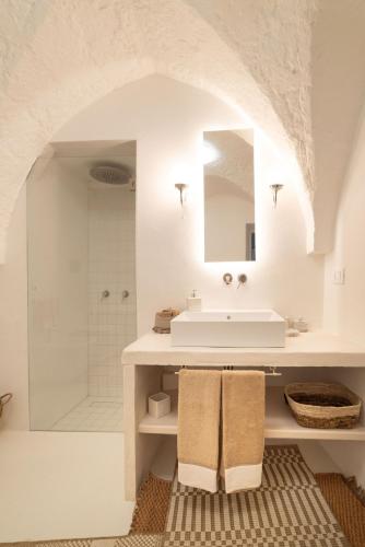 a white bathroom with a sink and a shower at Masseria Buganvillea in Fasano