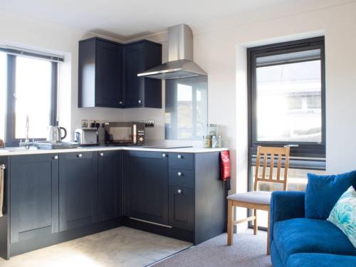 a kitchen with black cabinets and a blue couch at Chalet The Studio by Interhome in Glendale