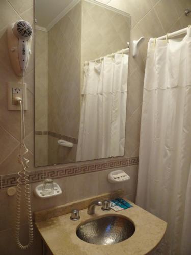 a bathroom with a sink and a mirror and a shower at Hotel Holimasú in Colón