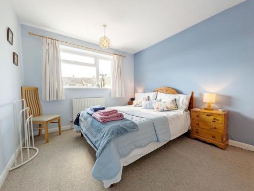 a blue bedroom with a bed and a window at Orchard Mews , Barnham in Barnham