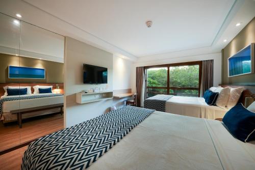 a large bedroom with two beds and a television at Salinas Maragogi All Inclusive Resort in Maragogi