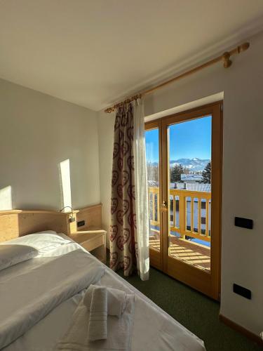 a bedroom with a bed and a balcony with a view at Hotel Alpe Bellaria in Candriai