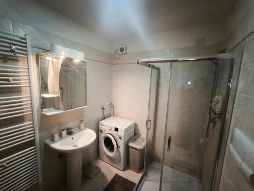 a bathroom with a shower and a sink and a washing machine at Good Time house in Aprilia Marittima