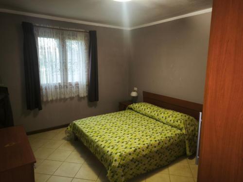 a bedroom with a bed with a yellow comforter and a window at Good Time house in Aprilia Marittima