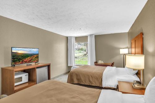 a hotel room with two beds and a flat screen tv at Bristol Arcadia Inn in Bristol