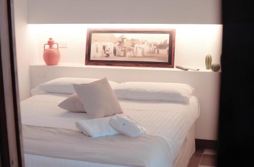 a bedroom with two white beds with a picture on the wall at BORGANTHIA in Alberobello