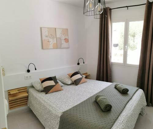 a bedroom with a bed with pillows and a window at Villa Brehat avec piscine privée in Cala en Porter