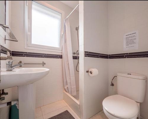 a bathroom with a toilet and a sink and a window at Villa Brehat avec piscine privée in Cala en Porter