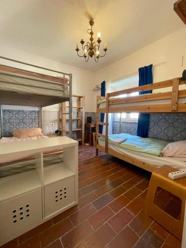 a room with two bunk beds and a chandelier at Native Surfhouse in Praia da Areia Branca