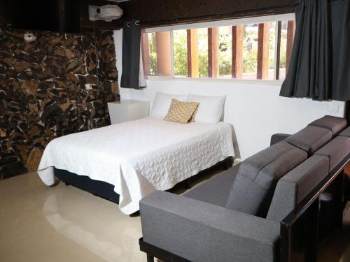 a bedroom with a bed and a couch and a chair at Hotel Casa Patrón Parras in Parras de la Fuente
