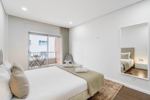 a white bedroom with a bed and a large window at Libertà Lodge Apartment - Minho's Guest in Braga