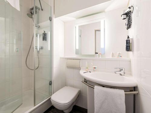 a white bathroom with a sink and a shower at ibis Hotel Regensburg City in Regensburg