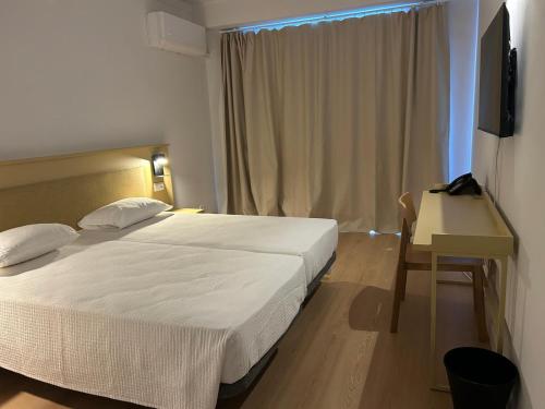 a bedroom with a bed and a desk and a television at Flag Hotel Campo Maior in Campo Maior