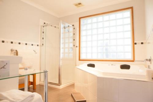 a white bathroom with a sink and a shower at bluebird cottage in Angaston