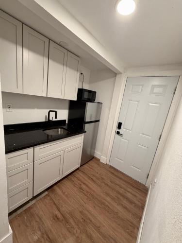 a kitchen with white cabinets and a sink and a door at Suite Safari in Tampa