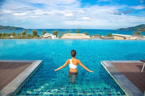 a woman standing in the water in a swimming pool at Beachfront and Deluxe Pool Access Patong Phuket in Patong Beach