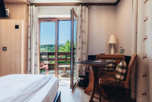 a bedroom with a bed and a desk and a window at Hotel Spa et Restaurant Au Chasseur in Birkenwald