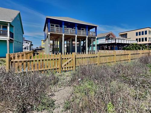 a house on the beach with a wooden fence at Beachfront Blue in Galveston