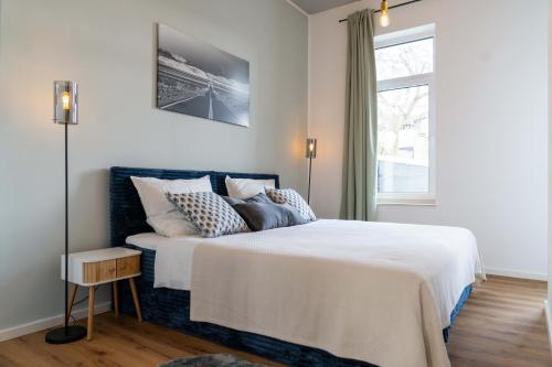 a bedroom with a white bed with pillows and a window at Boutique Apartment 74 in Krefeld
