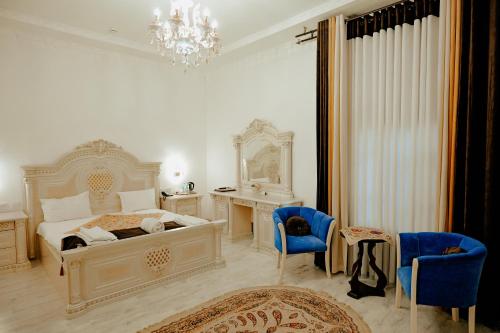 a bedroom with a bed and a desk and chairs at Imperial Palace Bukhara in Bukhara