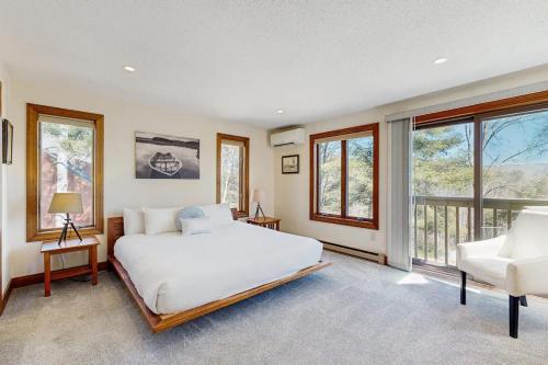 a bedroom with a large white bed and windows at Saltbox 12F in White River Junction
