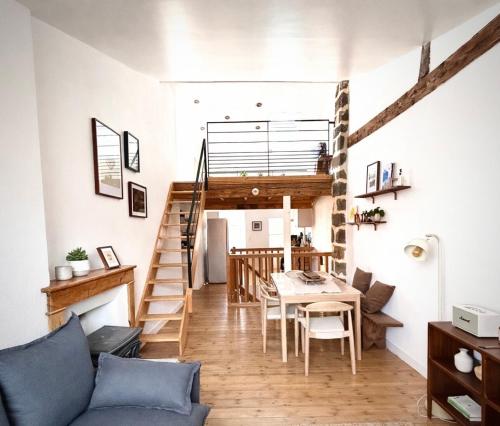 a living room with a staircase and a table and chairs at Maison atypique - Au coeur de la vieille ville in Le Puy-en-Velay