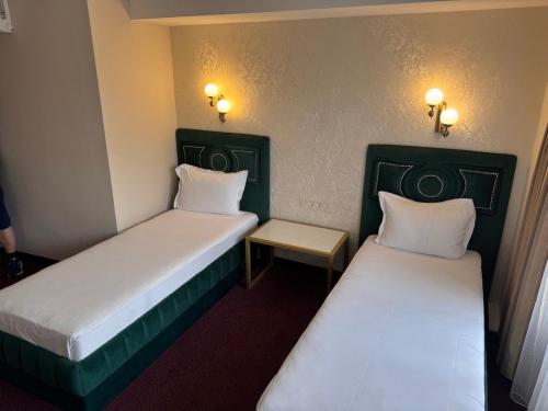 Zwei Betten in einem kleinen Zimmer mit Wandleuchten in der Unterkunft Hotel Dafi in Plowdiw