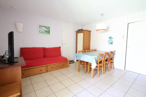 a living room with a red couch and a table at Swing Moliets - T2 bis - Golf - 3 Piscines - Plage in Moliets-et-Maa