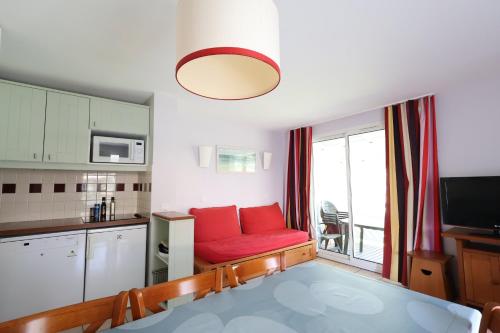 a living room with a red couch in a kitchen at Swing Moliets - T2 bis - Golf - 3 Piscines - Plage in Moliets-et-Maa