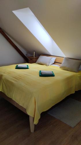 a large yellow bed with two pillows on it at Podkroví s koupelnou in Svinařov