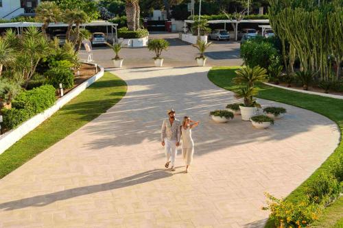 a man and a woman walking down a walkway at Hotel Lido Torre Egnazia in Monopoli