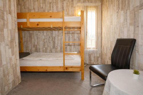 a bunk bed in a room with a table and a chair at Ádám nyaralóház in Balatonalmádi