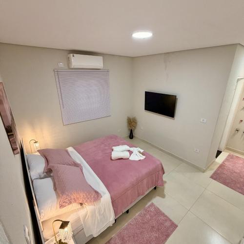 a bedroom with a bed with pink sheets and a tv at Chalé Rosa - Top Country Ranch in Boituva