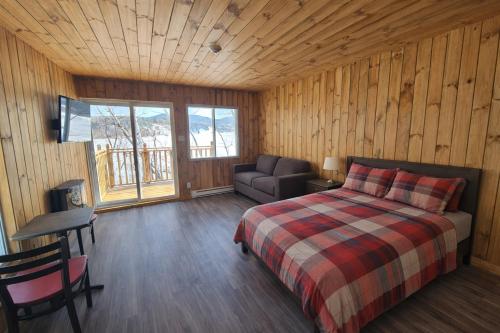 ein Schlafzimmer mit einem Bett, einem Stuhl und einer Couch in der Unterkunft Parc Octopus in Desbiens