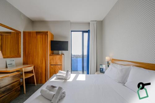 a bedroom with a bed with a desk and a window at Hotiday Chioggia Lungomare in Sottomarina