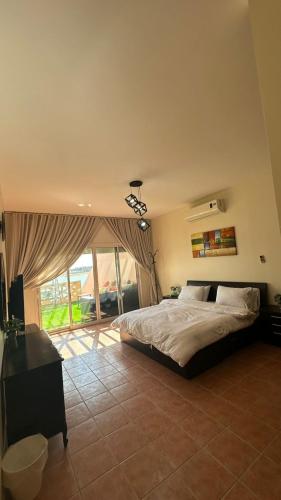 a bedroom with a bed and a large window at LA Brisa Durrat Alarous شاليهات لابريزا درة العروس شاطئ البرادايس للعوائل فقط in Durat Alarous