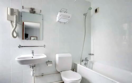 a white bathroom with a toilet and a sink at Hotel Royal Mansart in Paris