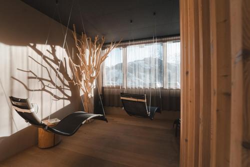 a room with chairs and a tree in a room at Hotel Weiler - Aktiv & Tradition in Obertilliach