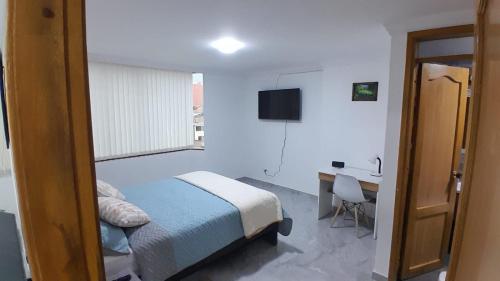 a bedroom with a bed and a desk and a window at El Encanto in Duitama