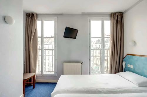a hotel room with a bed and two windows at Hotel Royal Mansart in Paris