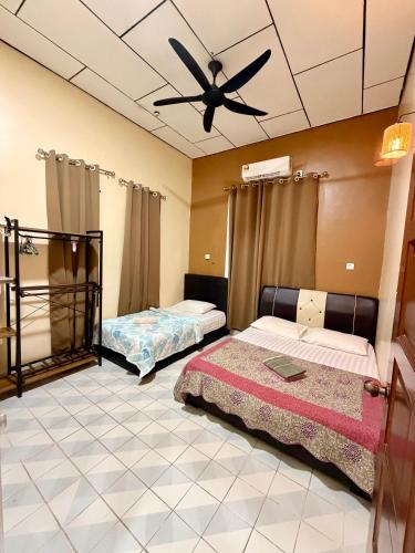 two beds in a room with a ceiling fan at NorvillaB Pantai Cenang in Pantai Cenang
