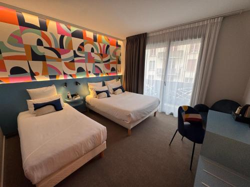 a hotel room with two beds and a painting on the wall at Urban Style L'Etape in Saint-Flour