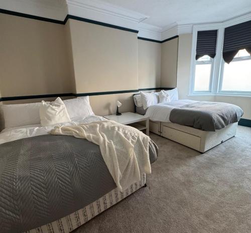 a bedroom with two beds and two windows at Spacious 2 BR Flat in Gateshead - Free Parking in Gateshead