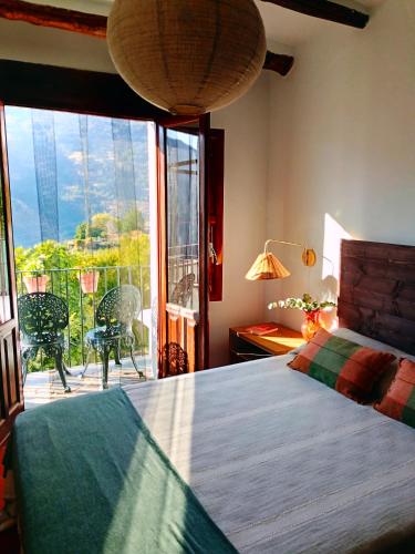 a bedroom with a bed and a balcony with a view at La Locana in Bubión