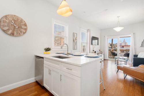 a white kitchen with a sink and a living room at Jennifer's Chic Downtown City Views Private Deck in Providence