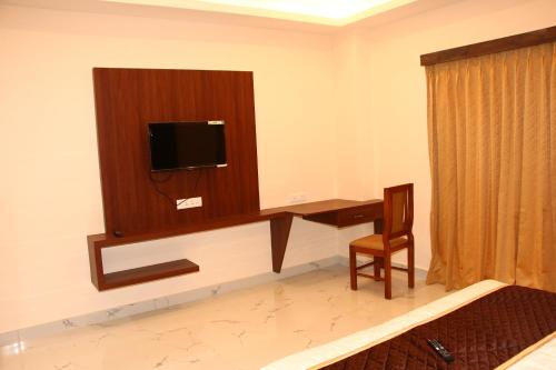 a room with a desk and a tv on a wall at sas square hotels in Tiruchirappalli